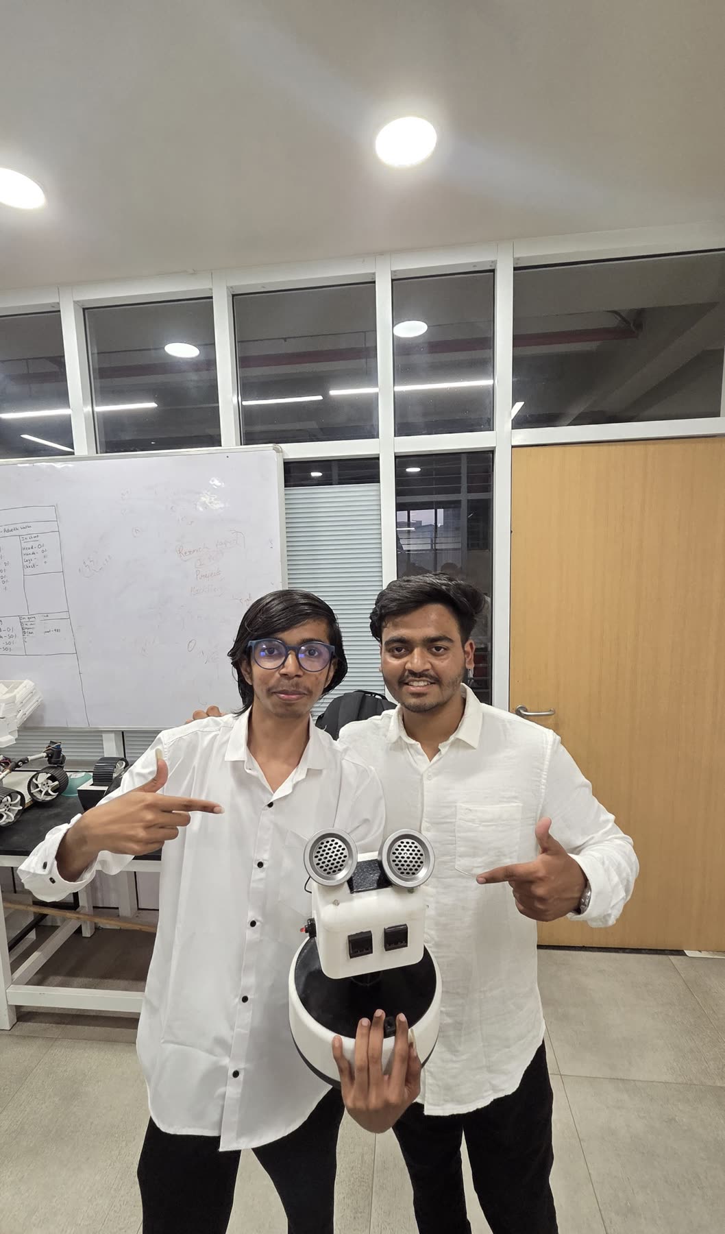 Two Yantrix members pointing at the robot they are holding